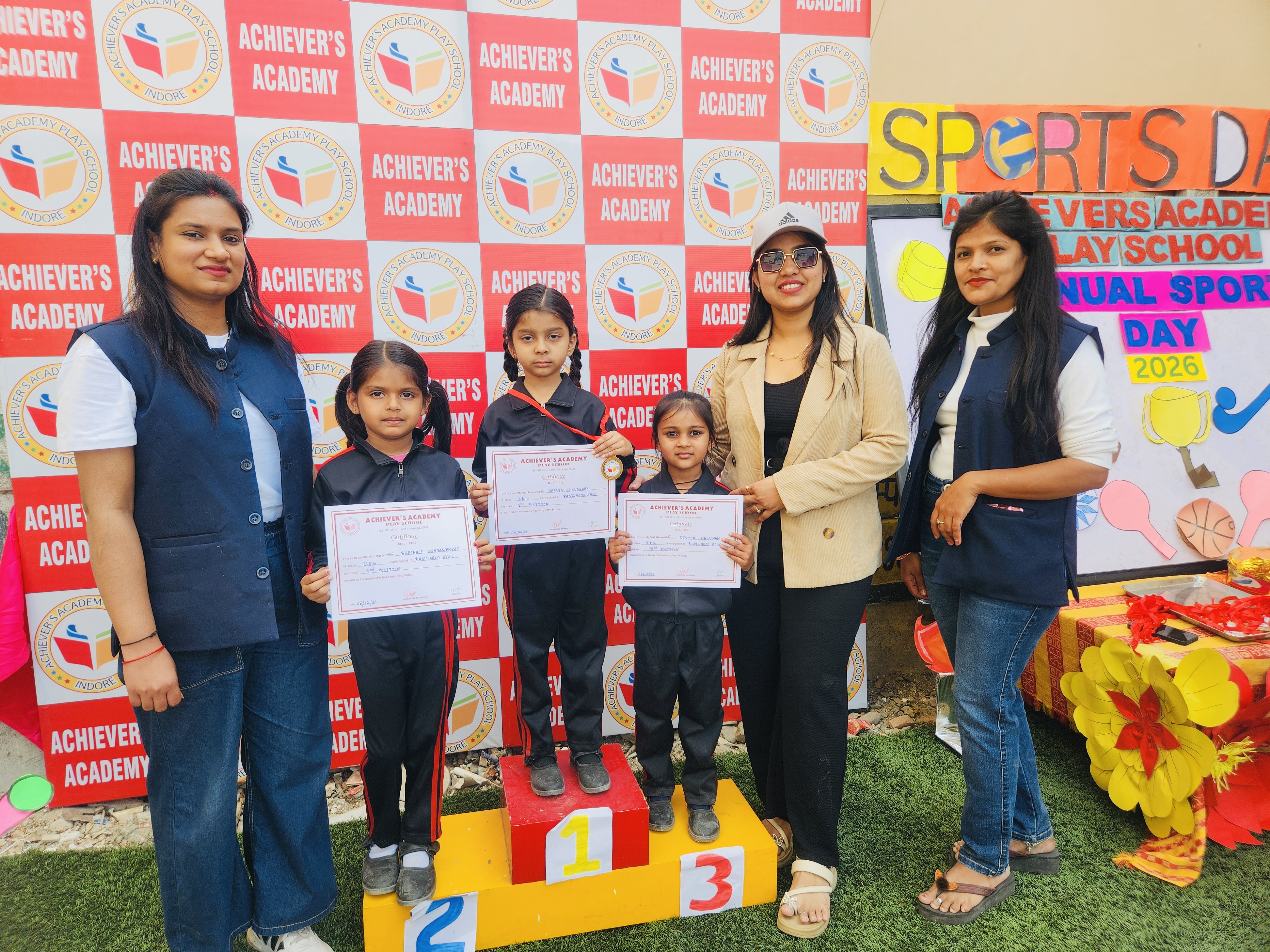 Annual Sports Day Prizes - Students holding certificates on podium with teachers